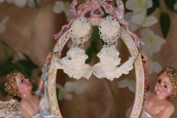 A pair of earrings hanging from the side of a mirror.