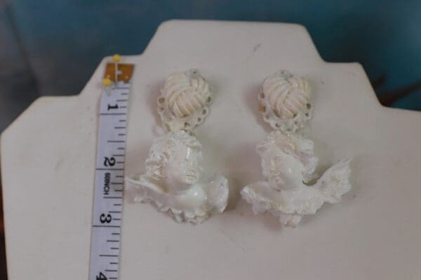 A pair of white earrings sitting on top of a table.