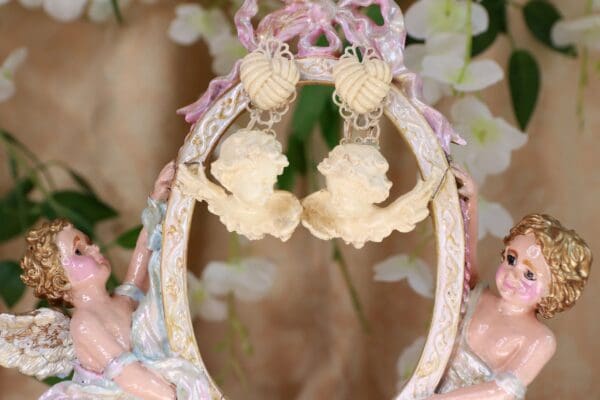 A pair of earrings hanging from the side of a mirror.