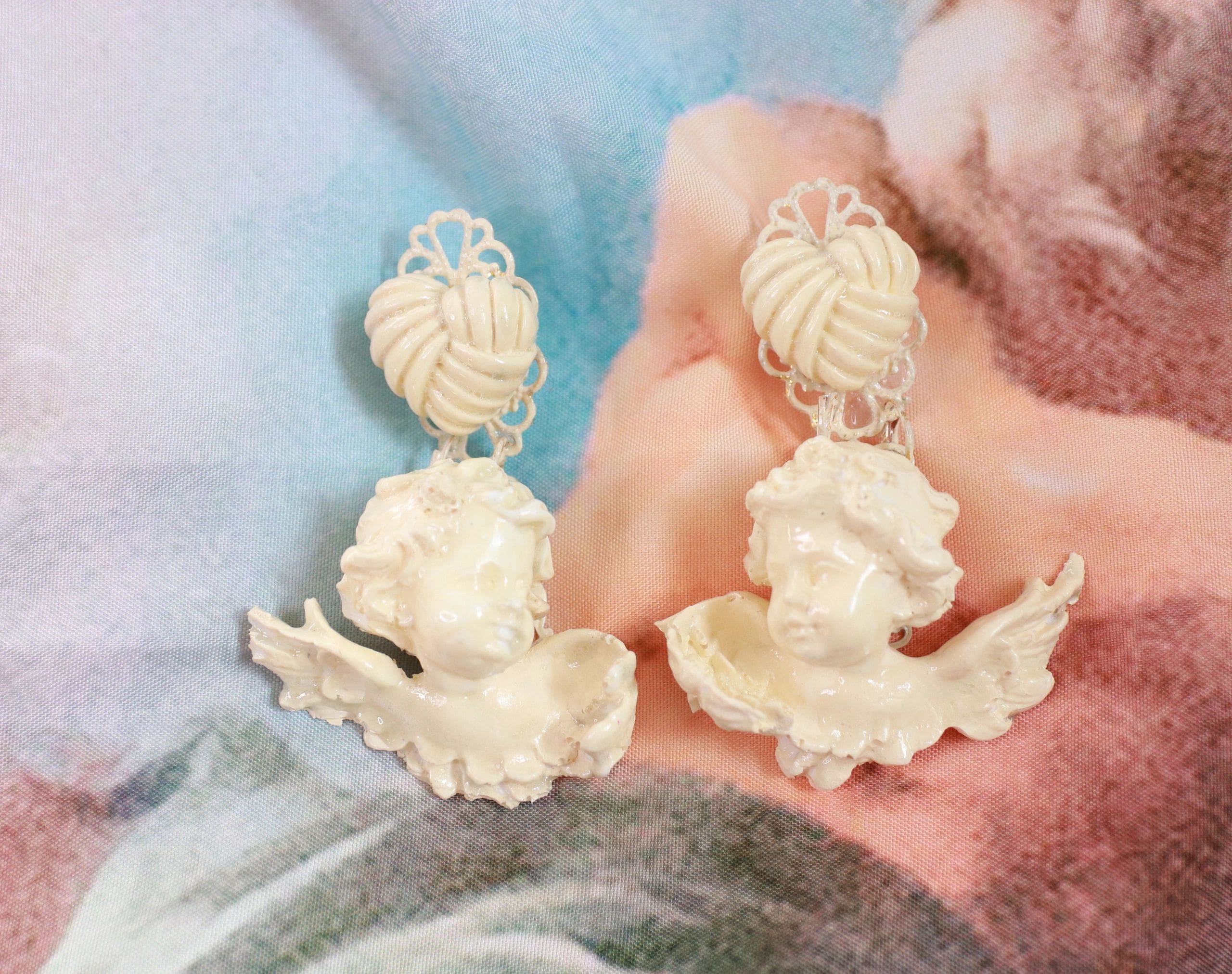 A pair of earrings with white shells and faces.