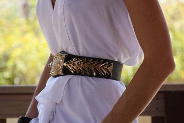 A woman wearing a white dress and black belt.
