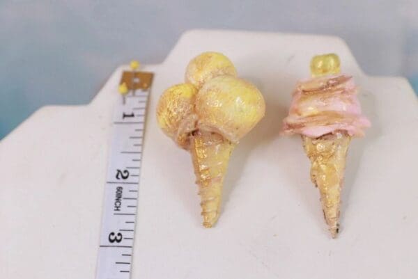 A pair of ice cream cones are shown next to a ruler.