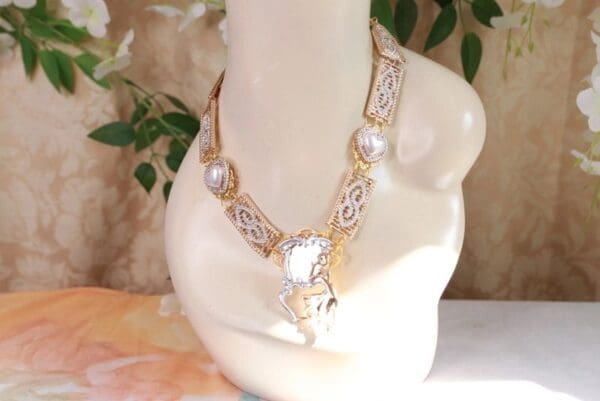 A necklace with pearls and gold chain on top of a white table.