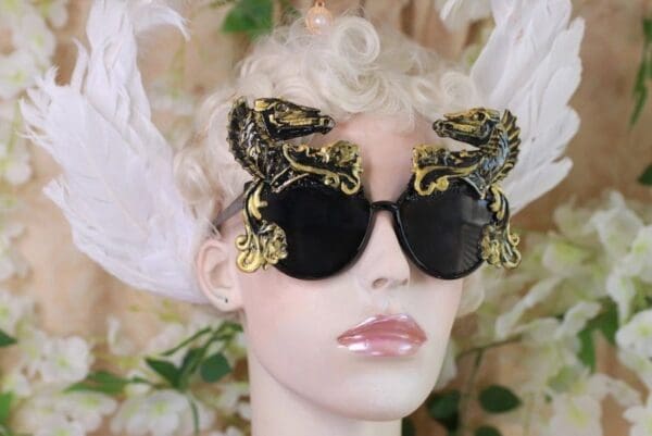 A mannequin wearing sunglasses with gold dragon 's on them.