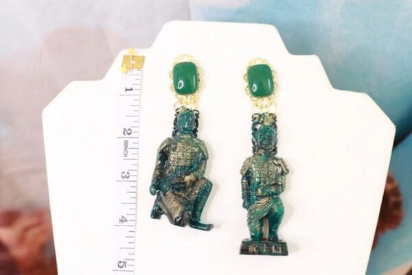 A pair of green earrings sitting on top of a white table.