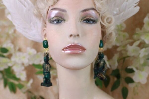 A mannequin wearing green earrings and a wig.
