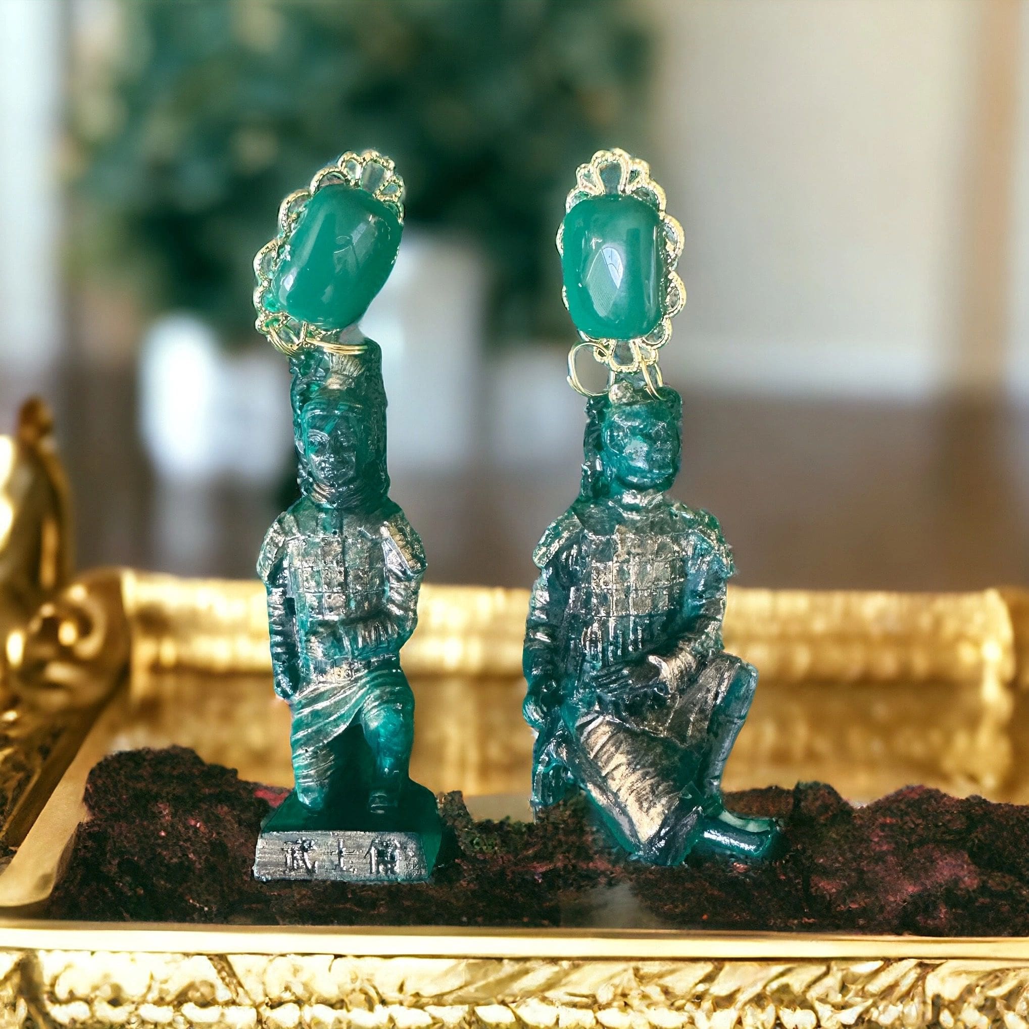 Two green statues are sitting on a gold tray.