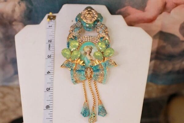 A large green and blue brooch is on the table.