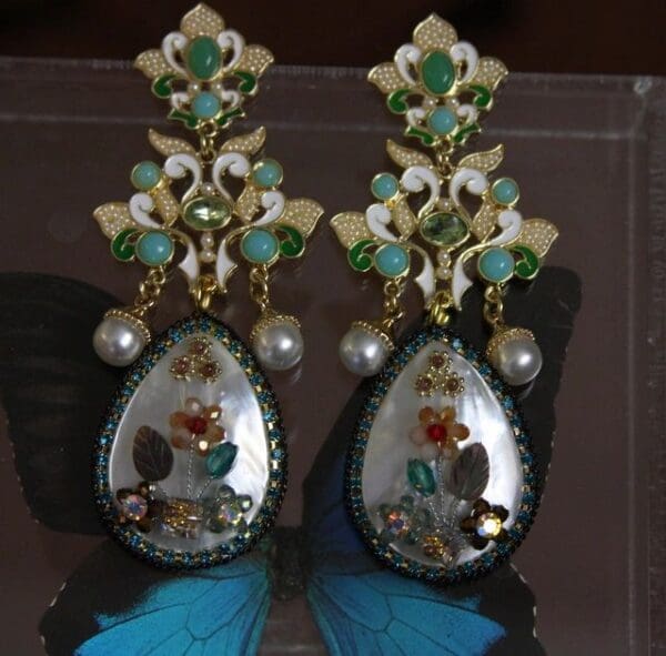 A pair of earrings with green and white stones.