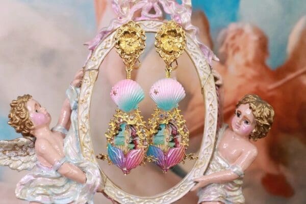 A pair of earrings with gold and pink beads.