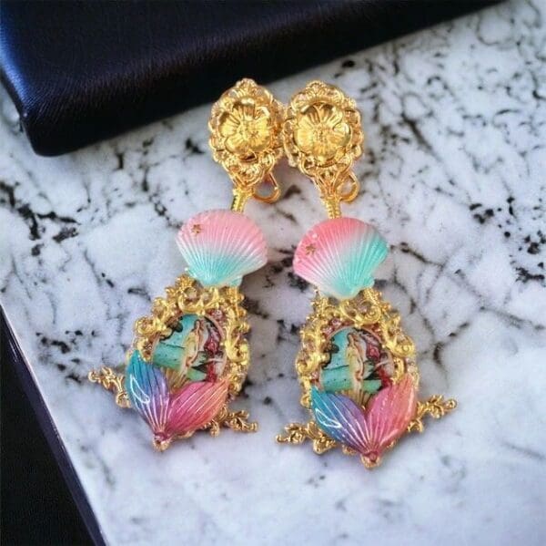 A pair of earrings with gold chains and pink, blue and green stones.