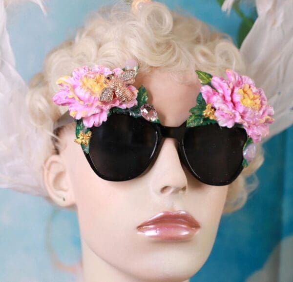 A blonde woman wearing sunglasses with pink flowers on them.