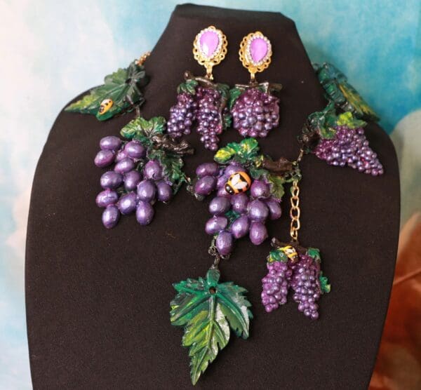 A necklace and earrings set with purple grapes.