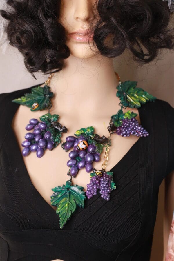 A woman wearing a necklace with grapes on it.