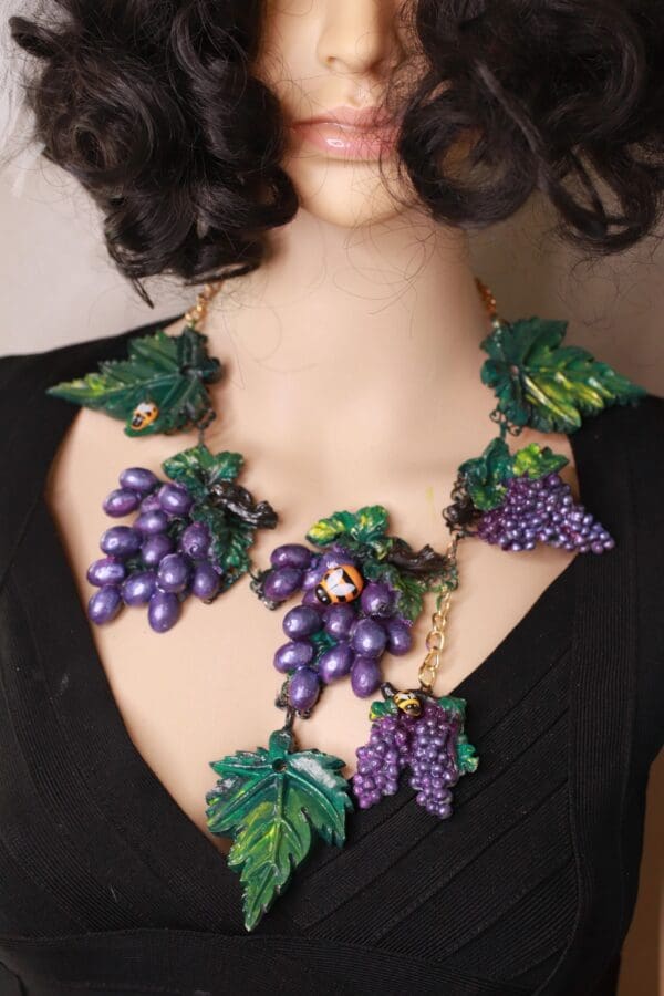 A woman wearing a necklace with grapes on it.