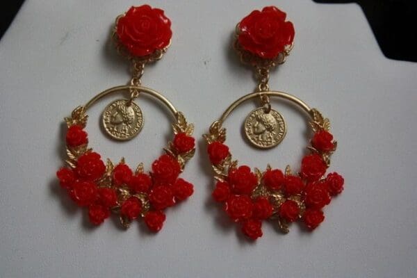 A pair of red earrings with gold coins and flowers.