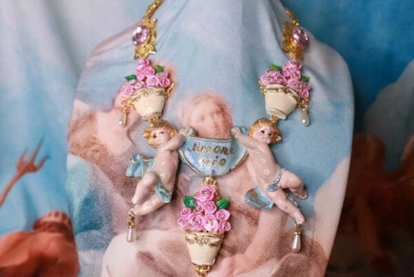 A necklace with pink flowers and angels on it.