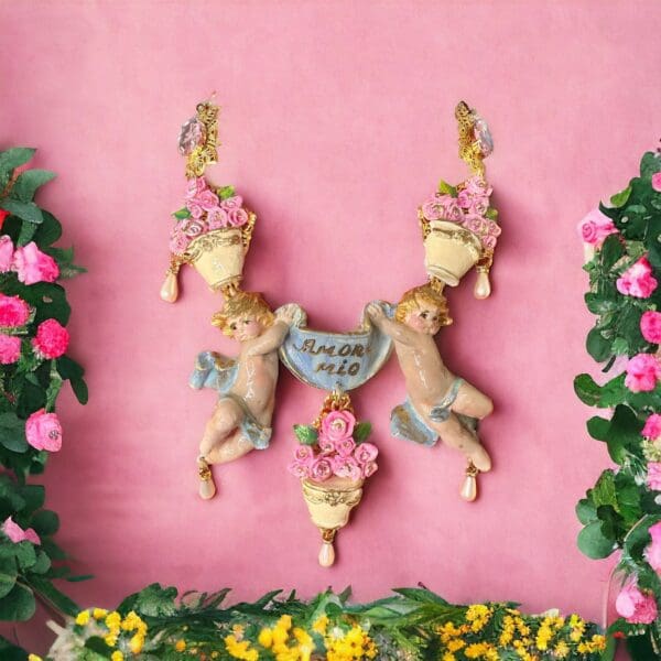 A pink wall with two angels hanging from it.
