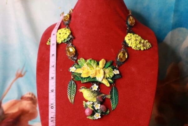 A red necklace with yellow flowers and green leaves.