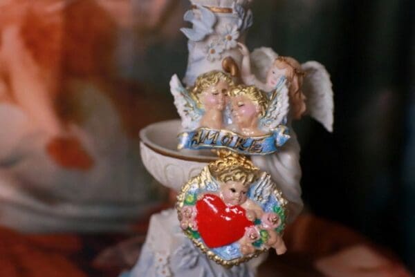 A close up of two angels on top of a candle