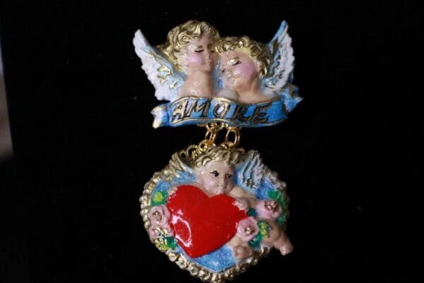 A couple of angels are hanging from the side of a heart