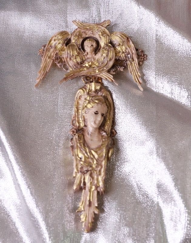 A gold statue of an angel with wings and a head.