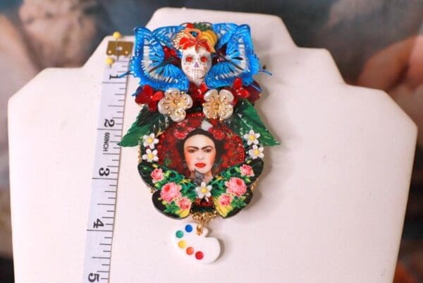 A large brooch with frida kahlo and the artist 's palette.