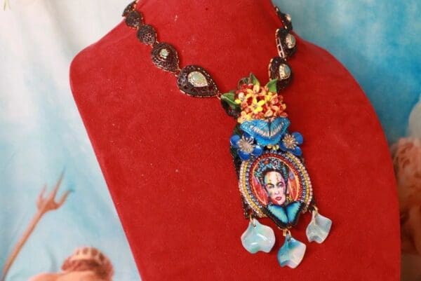 A red display with a necklace and a portrait of frida kahlo.