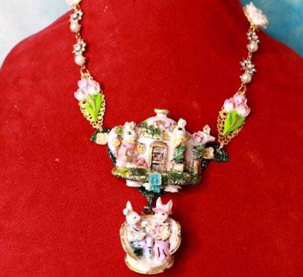 A necklace with pink flowers and green leaves.