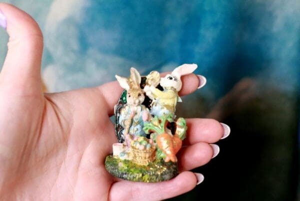 A person holding a small statue of bunnies.