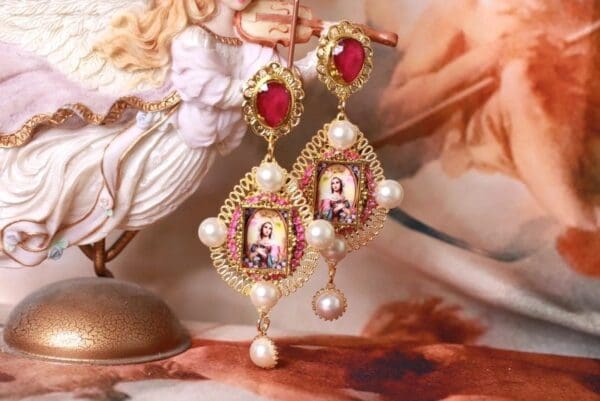 A pair of earrings with pearls and pictures on them.