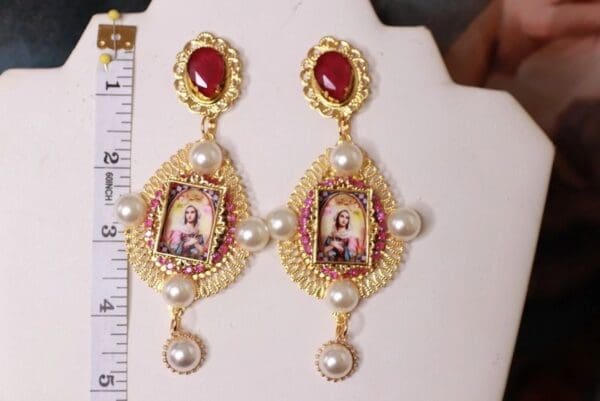 A pair of earrings with pictures and pearls.