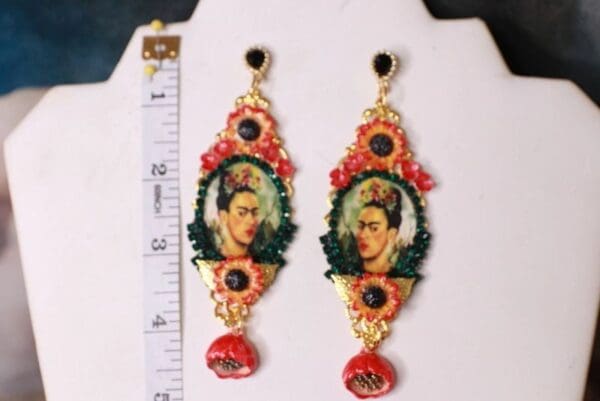 A pair of earrings with a picture of frida kahlo.