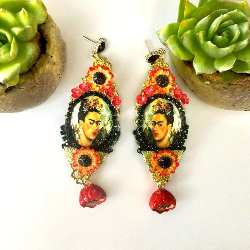 A pair of earrings with a picture of frida kahlo.