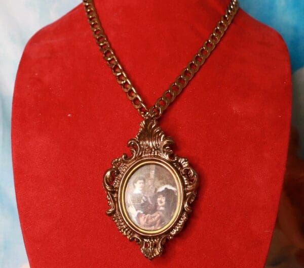 A red velvet display with a necklace and picture