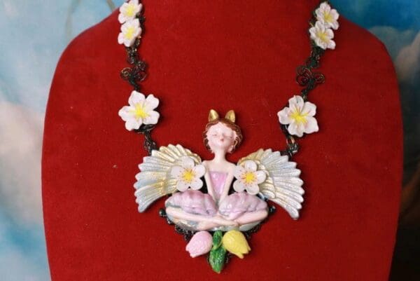 A necklace with a fairy sitting on top of it.