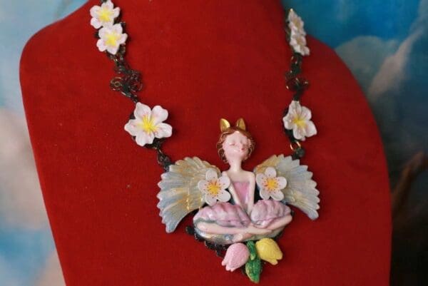 A necklace with flowers and a fairy on it.