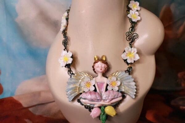 A necklace with a fairy sitting on top of it.