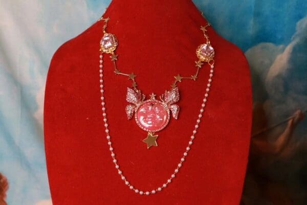A red necklace with a pink butterfly and star on it.