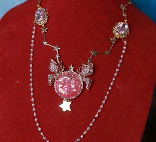 A red velvet display with a necklace and a pink pendant.