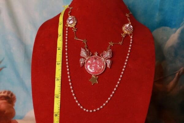 A red necklace with a pink butterfly and star on it.