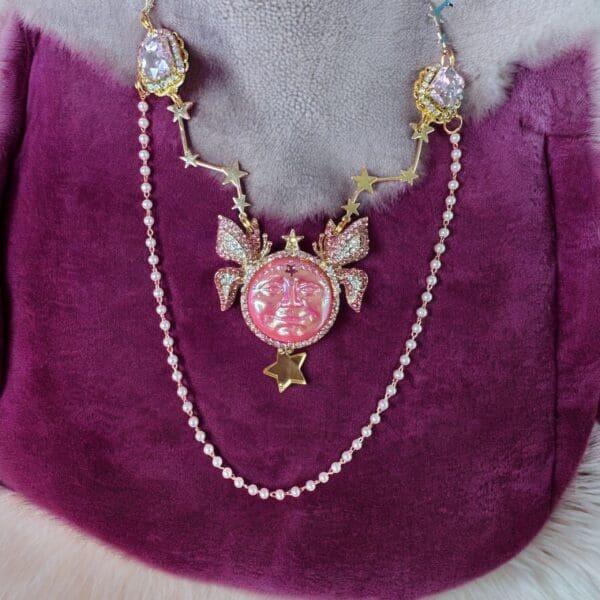 A pink necklace with pearls and gold on top of it.