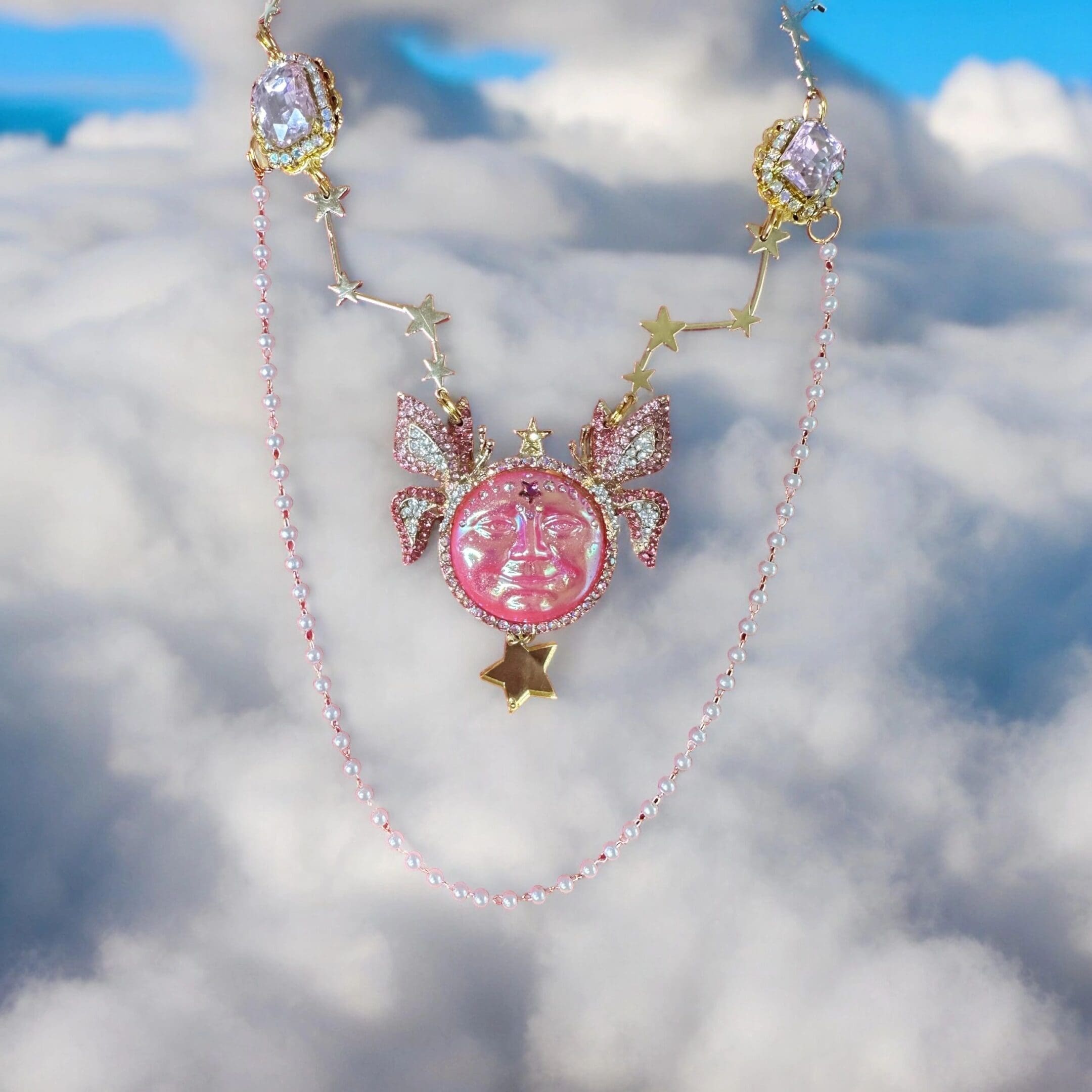 A pink necklace with a star and a unicorn on it.