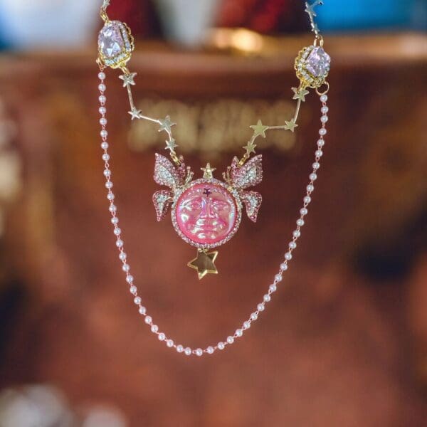 A pink necklace with pearls and a butterfly.