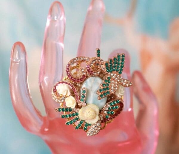A pink hand with a ring on it