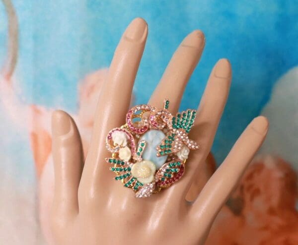 A hand wearing a ring with a picture on it