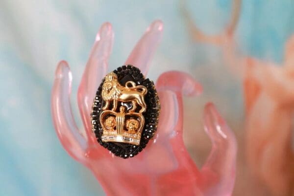 A hand holding a ring with a lion on it.