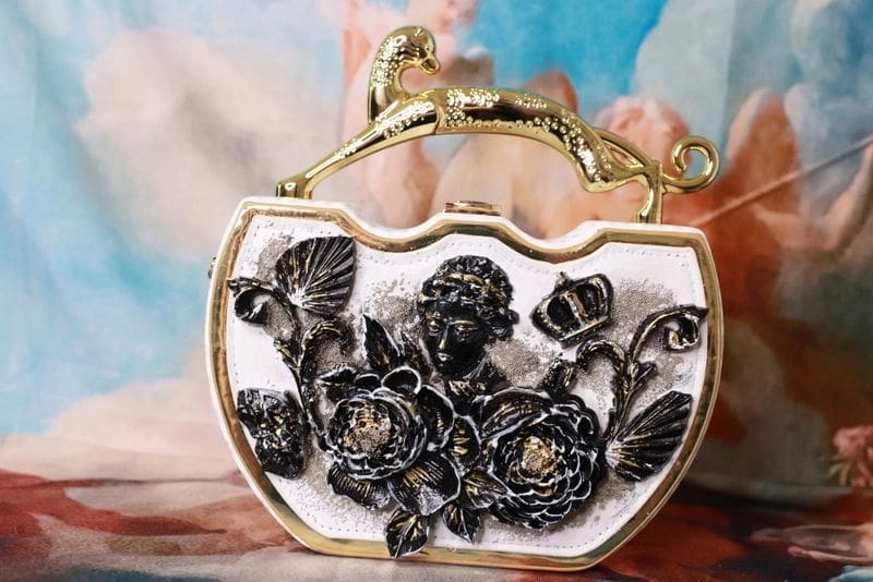 A purse with gold and black flowers on it.