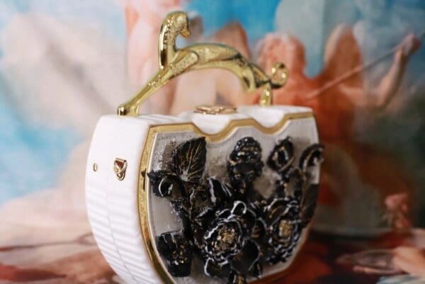 A white purse with gold and black flowers on it.