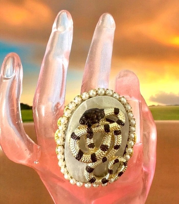 A pink hand with a white and black ring on it